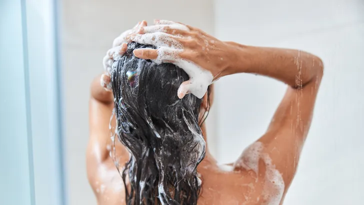 vrouw wast haar onder de douche