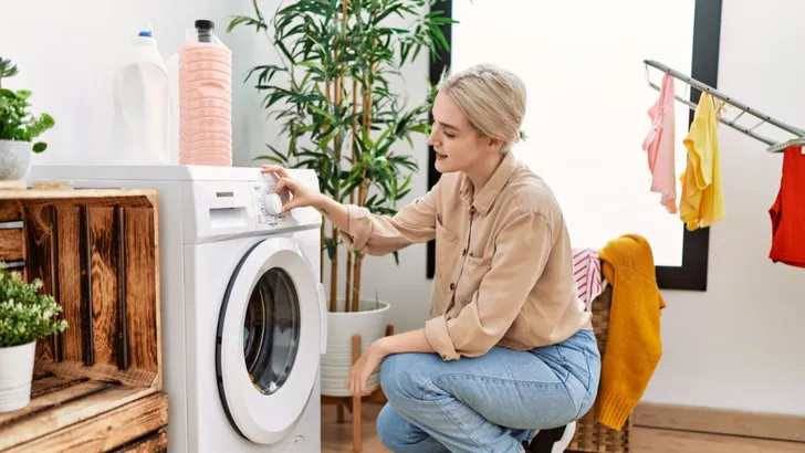 Vrouw doet was in de wasmachine.