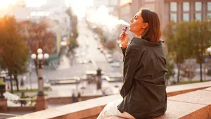 Woman at sunset with amazing city view, enjoying warm days, freedom, positive vibes, smoking  electronic cigarette