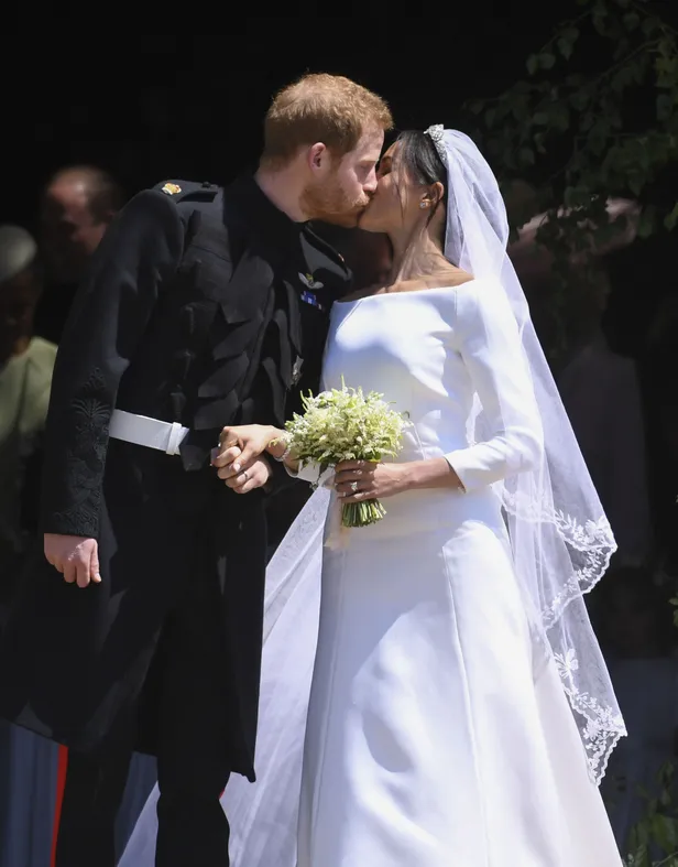 Meghan Markle en prins Harry geven elkaar een romantische kus na hun sprookjesbruiloft in St. Georges Chapel in 2018.