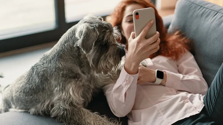 vrouw zit op haar telefoon met haar hond naast zich