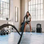 A woman is doing exercises with a rope at the gym