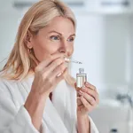 Pretty elegant female with face skin care in hand in bathroom