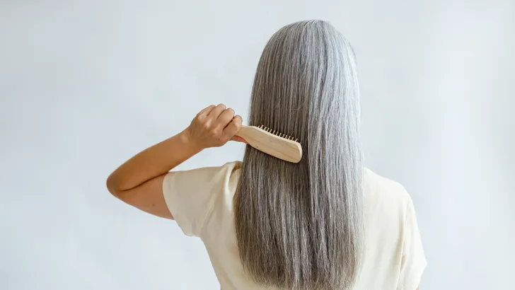 Haircare op leeftijd: zó verandert je haar met de jaren – Vrouw met grijs haar en haarborstel.