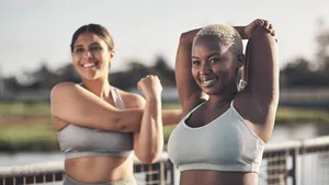 Shot of two young women stretching while outside for a workout