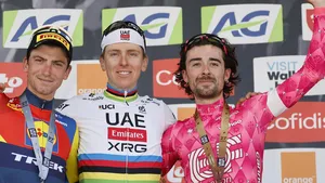 Ben Healy en Tadej Pogacar op het podium van Luik-Bastenaken-Luik, Healy in roze EF-trui met medaille, Pogacar in regenboogtrui.