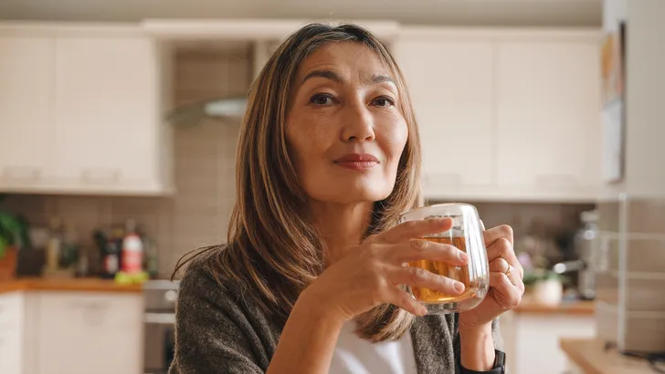 Een vrouw van middelbare leeftijd geniet van haar eerste drankje na intermittent fasting.