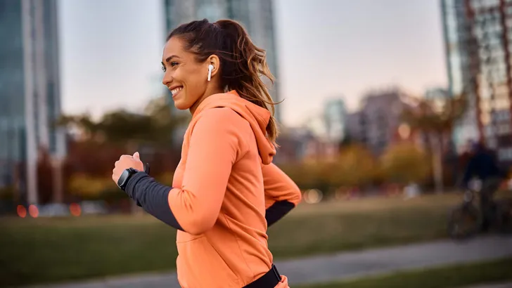 Happy female athlete running while exercising outdoors.