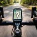 Fietscomputer op het stuur met kaart op het scherm en een groot vraagteken, gefotografeerd vanuit het perspectief van de fietser op een bosweg.
