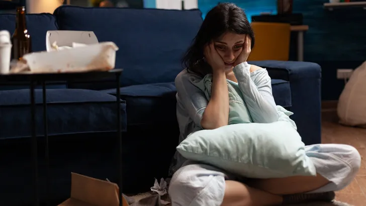 Lonely, traumatised, frustrated, ill woman holding head in hands, feeling vulnerable