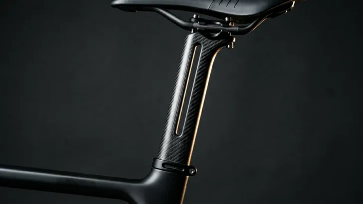 Studio close-up in profiel van een innovatieve, in tweeën gespleten carbon zadelpen op een racefiets, ontworpen als bladveer om trillingen te absorberen.