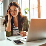 Tired business woman in stress works at a laptop while sitting a