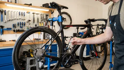 Close-up van een fietser die een witte druppel vloeibare kettingwax op de schone kettingschakels van een racefiets aanbrengt.