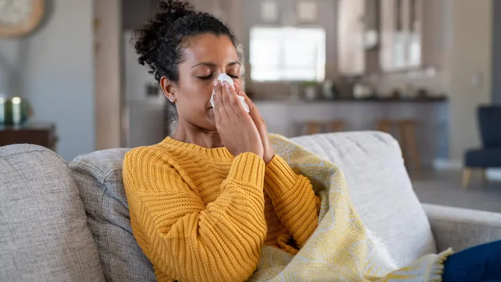 Cold sick african woman blowing nose