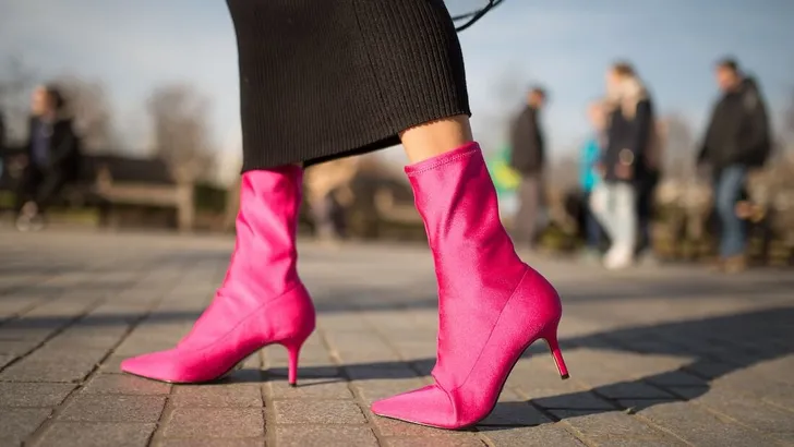 A close up shot of a young fashionable woman walking in the hot pink sock boots. Cocnept of fashion, foortwear and street style. Spring and autumn outfit ideas.