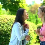 Two female friends arguing outdoors, relations confrontation, communication