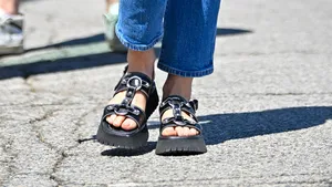 Vrouw draagt zwarte sandalen op een hete zomerdag