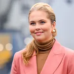 Amalia lachend in roze jas en beige trui met haarband in haar