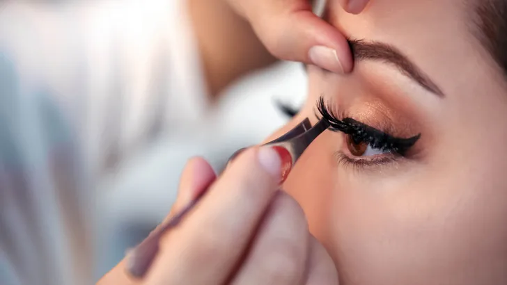 Makeup artist applying false eyelash