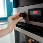 Close up of woman's hand setting temperature control on oven