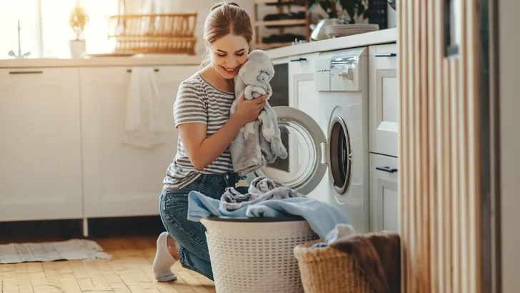 Happy housewife woman in laundry room with washing machine