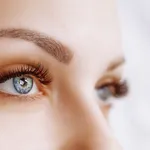 Eyelash Extension Procedure. Woman Eye with Long Eyelashes. Close up, selective focus