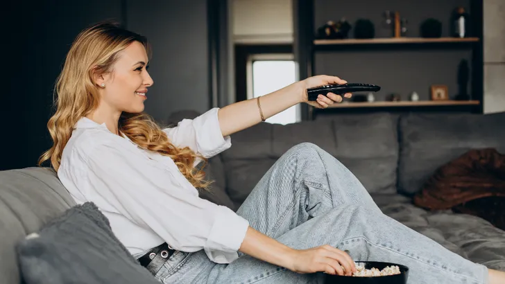 Foto van vrouw die tv kijkt met popcorn. – Abonnement tv en internet kiezen.