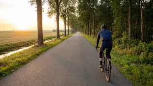 Man op racefiets rijdt over een rustige, landelijke weg tijdens zonsondergang, wat een gevoel van rust en mentale helderheid uitstraalt.