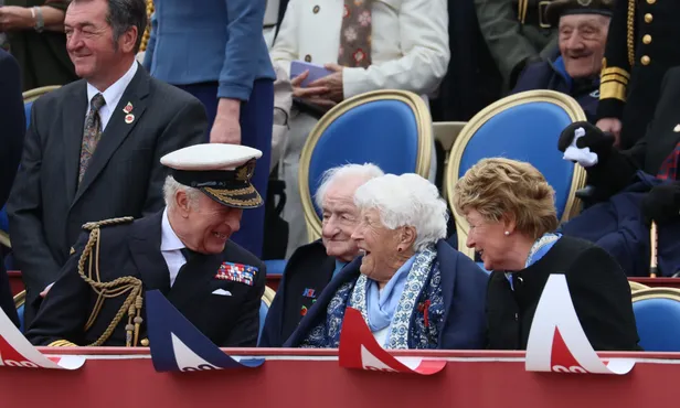 Koning Charles en Lady Sarah McCorquodal samen lachend op de tribune