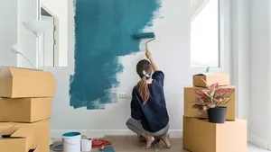 Young asian happy woman painting interior wall