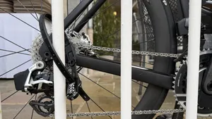 Close-up van een compact, zwart 'tiewrap'-stijl fietsslot vasthoudt om de kleine omvang en het driecijferige combinatieslot te laten zien.
