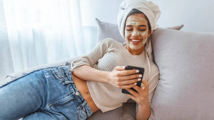 Woman use beauty mask with cellphone at home