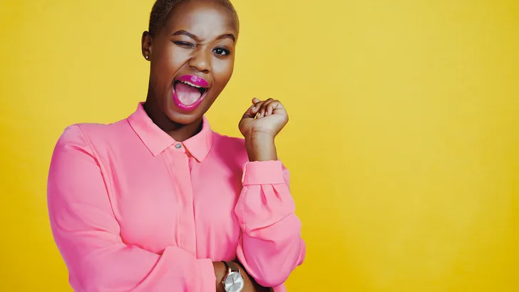 Cropped shot of an attractive and cheerful young woman winking in studio against a yellow background