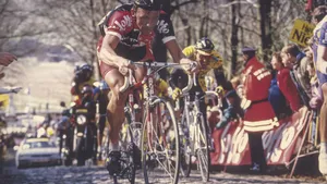 Mannelijke wielrenner met helm in een eenzame strijd op de steile kasseien van de Kemmelberg tijdens de wielerwedstrijd Gent-Wevelgem, met toeschouwers langs de kant van de weg.