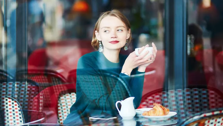 Young elegant woman drinking coffee in cafe in Paris, France