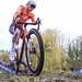 ereldkampioen veldrijden Mathieu van der Poel met een geconcentreerde blik en duidelijke modderspatten op zijn gezicht en regenboogtrui tijdens het WK in Hulst.