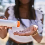 Young african american girl using sunscreen lotion at the beach.