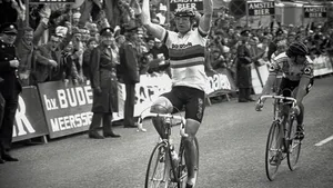 Jan Raas juicht met zijn armen in de lucht terwijl hij in de iconische regenboogtrui de Amstel Gold Race wint.