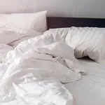 bed and white pillows with wrinkle blanket in bedroom