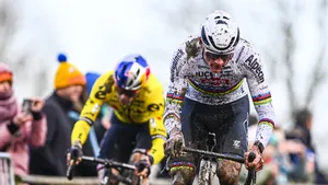 Mathieu van der Poel in de regenboogtrui op kop tijdens een modderige cross, met Wout van Aert daarachter