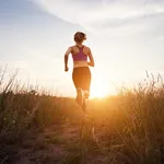 Young sporty girl running on a rural road at sunset