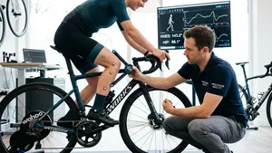 Een professionele bikefitter meet de kniehoek van een wielrenner op een high-end racefiets in een moderne bikefitting studio.