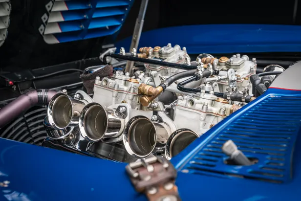 Close-up van vier glanzende carburateurtrompetten op de V8-motor van de Corvette Grand Sport.
