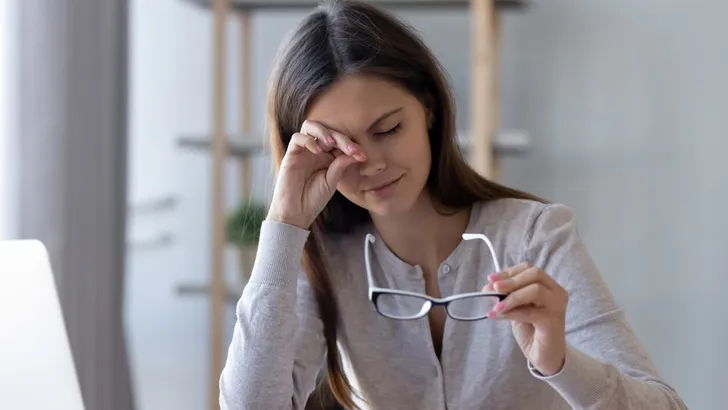 Tired woman rubbing eyes feeling fatigue from glasses computer work