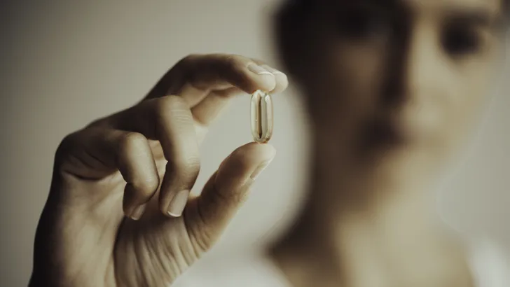 The focus is on the vitamin capsule.