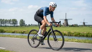 Wielrenner traint op krachtuithouding met een laag traptempo op een vlakke Nederlandse polderweg.