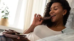 Happy woman enjoying her chocolate bar in bed.