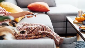 Woman with plaid selecting movie with remote controller 