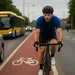 Wielrenner rijdt op een rood fietspad langs druk stadsverkeer met auto’s en een bus op de achtergrond.
