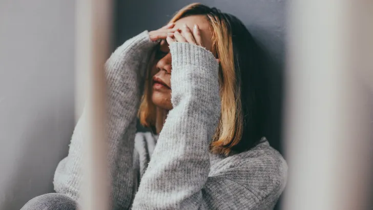 Depressed and sad young woman sitting alone at home